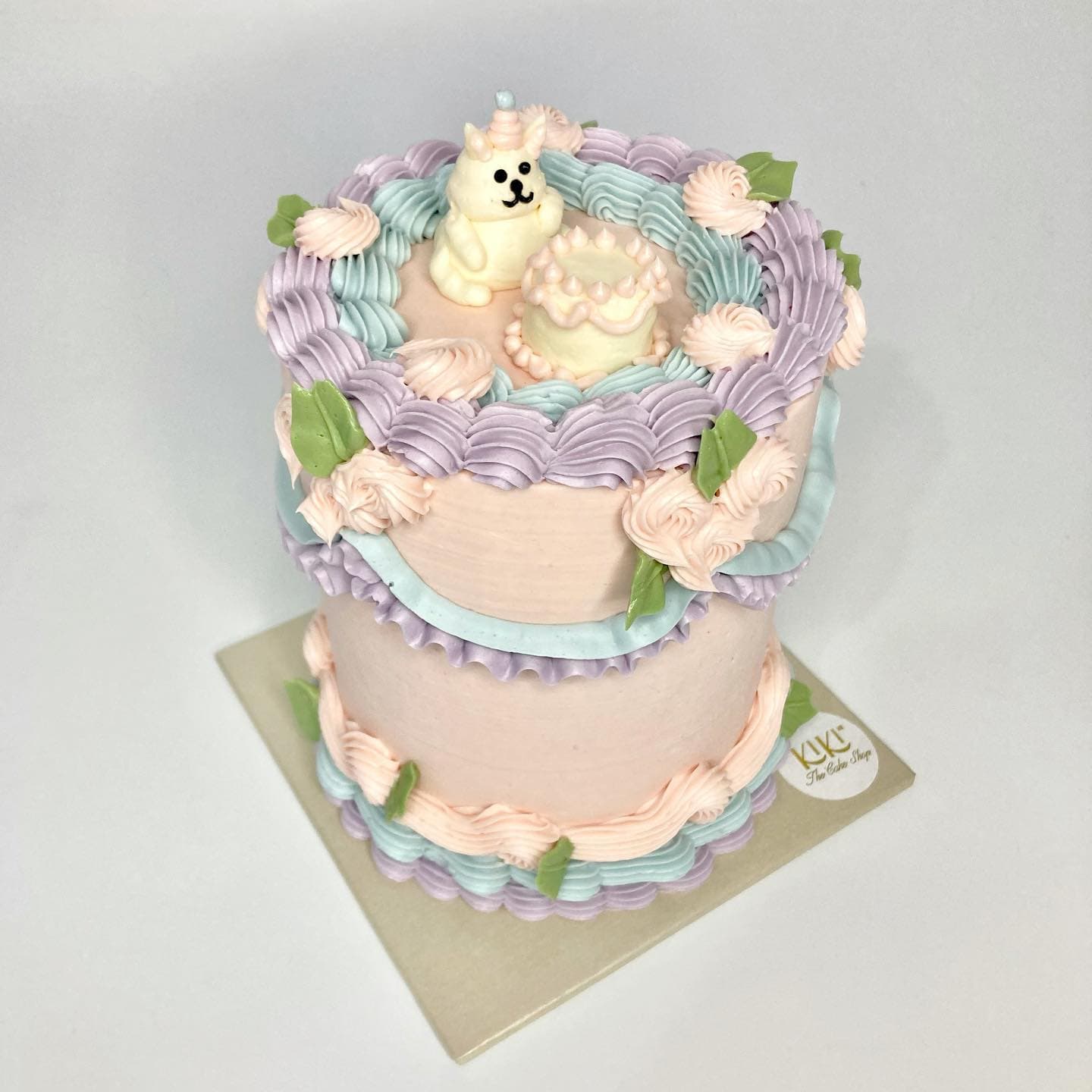 Pastel en tonos pastel con figura de conejito y mini pastel de topper